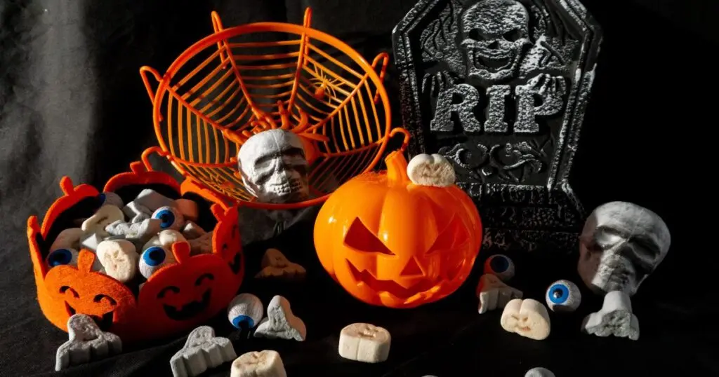 Adornos de Halloween con calabaza y calaveras Decoración de Halloween con calabaza naranja, calaveras, ojos y lápidas sobre fondo oscuro