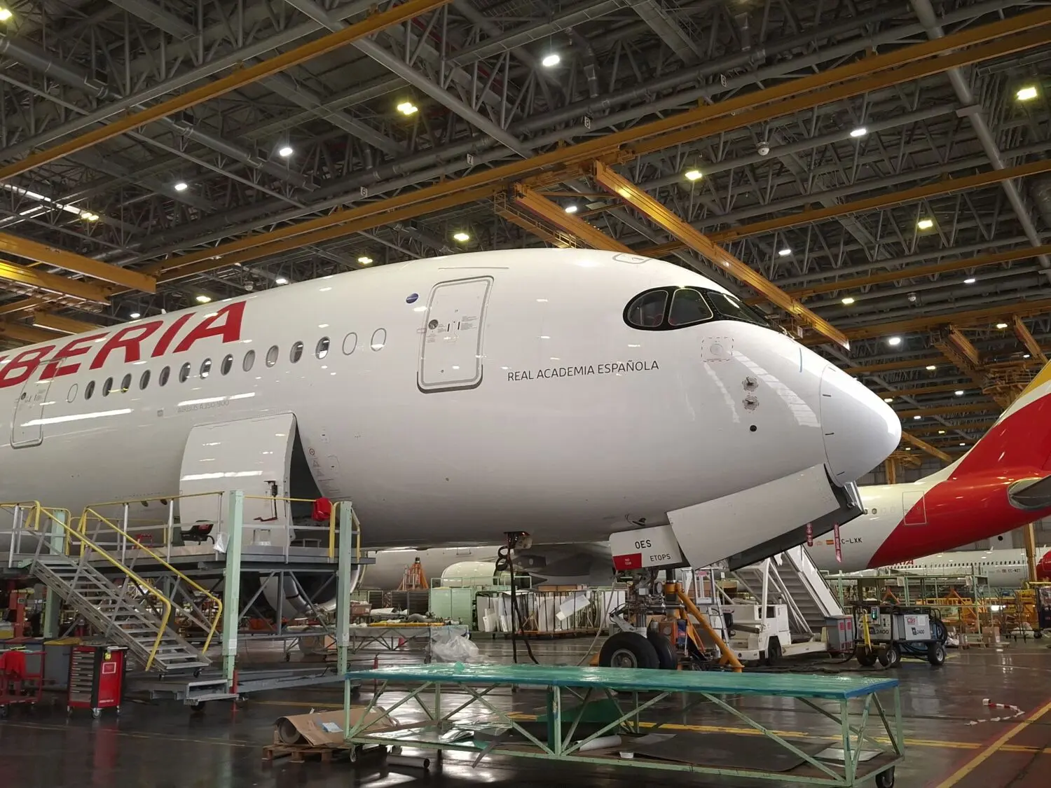 Airbus A350 de Iberia dentro de un hangar Avión Airbus A350 de Iberia dentro de un hangar, rodeado de equipos.