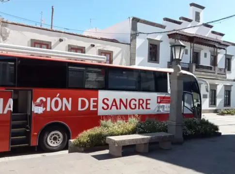 Unidad móvil de donación de sangre Autobús rojo de donación de sangre estacionado frente a un edificio blanco