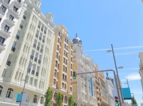 Avenida flanqueada por edificios urbanos Edificios urbanos de varios estilos junto a una avenida bajo un cielo azul.