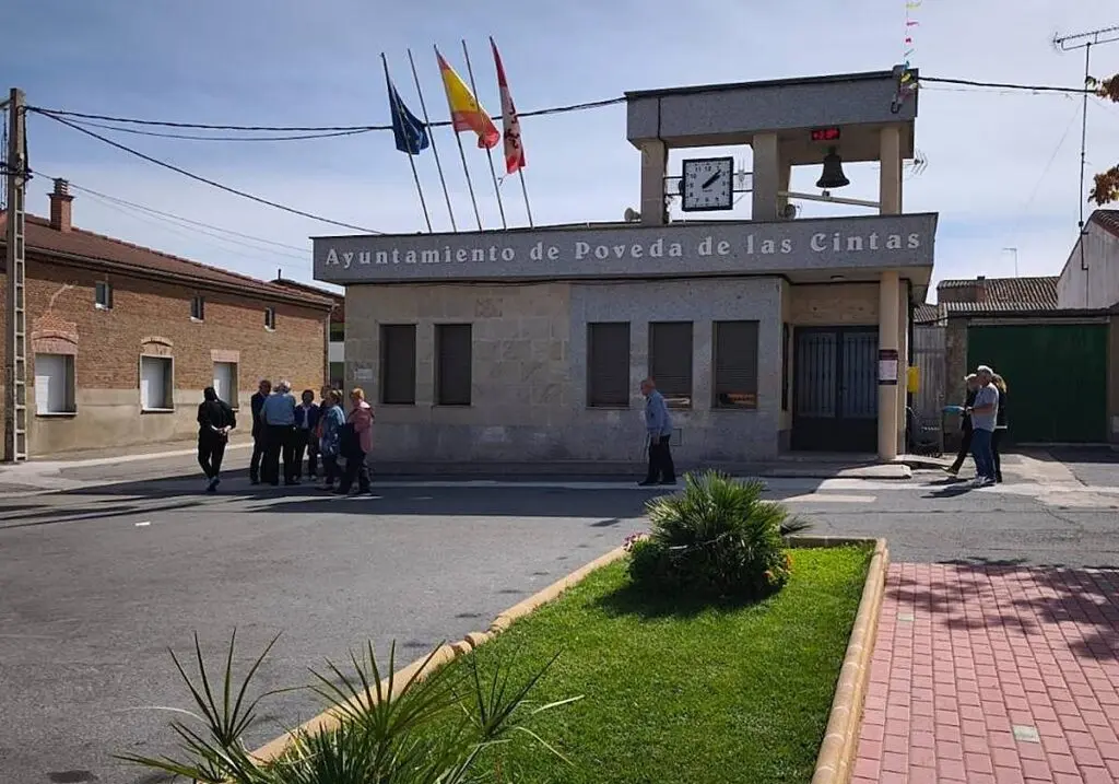 Edificio del Ayuntamiento de Poveda de las Cintas junto a varias personas en la plaza.