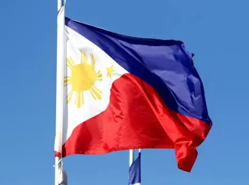 Bandera filipina ondeando bajo el cielo azul Bandera de Filipinas ondeando en un mástil frente a un cielo azul.