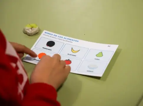 Bingo de alimentos en actividad educativa Una mano marca una casilla en un cartón de bingo ilustrado con alimentos.