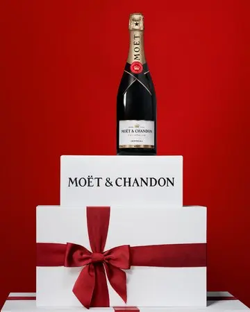 Moët & Chandon transforma sus botellas en regalos de lujo para Navidad con una novedad que se puede personalizar 1 Merca2 Botella de Moët & Chandon sobre cajas blancas con un gran lazo rojo.