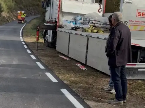 Carretera con marcas viales y camiones Carretera asfaltada con marcas blancas, varios camiones y personas junto al arcén.
