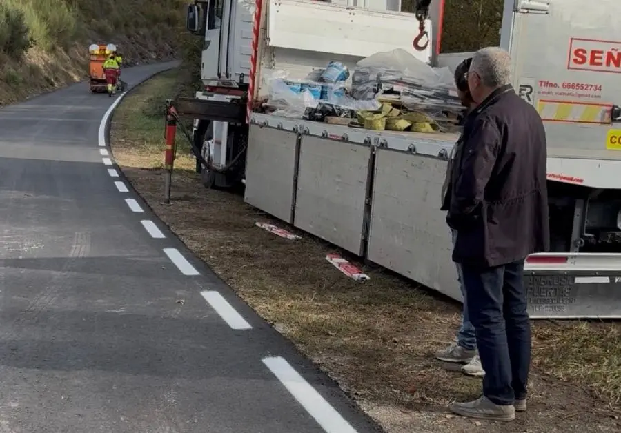 Carretera con marcas viales y camiones Carretera asfaltada con marcas blancas, varios camiones y personas junto al arcén.