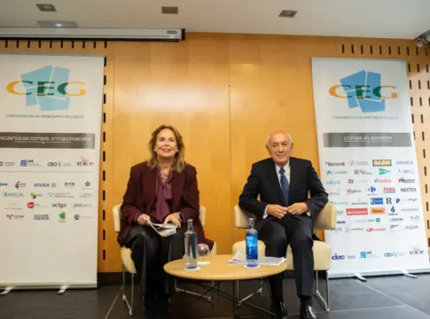 Dos personas entre paneles de la CEG Dos personas sentadas junto a una mesa, entre paneles de la CEG.