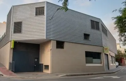 Edificio de varias plantas en una esquina, con fachadas claras y revestimiento metálico.