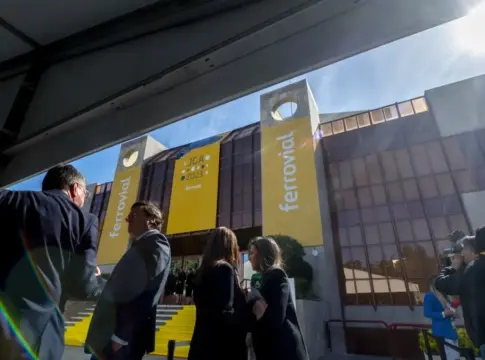 Edificio de Ferrovial con pancartas amarillas Personas frente a un edificio con grandes pancartas amarillas de Ferrovial.