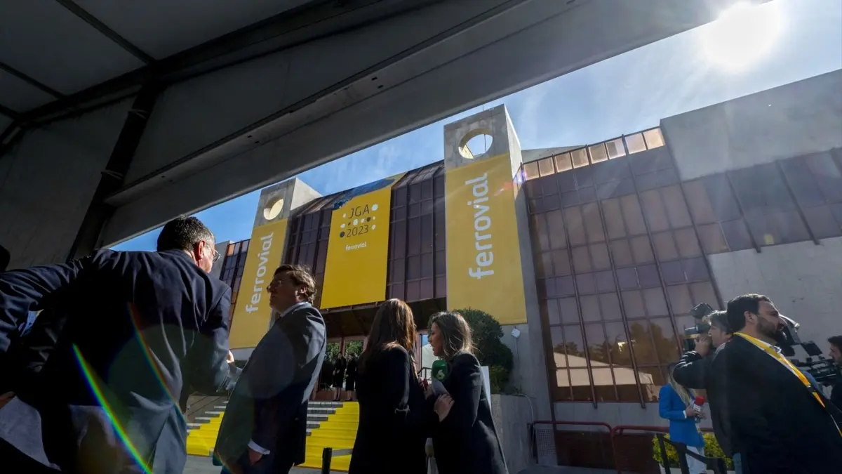 Personas frente a un edificio con grandes pancartas amarillas de Ferrovial.