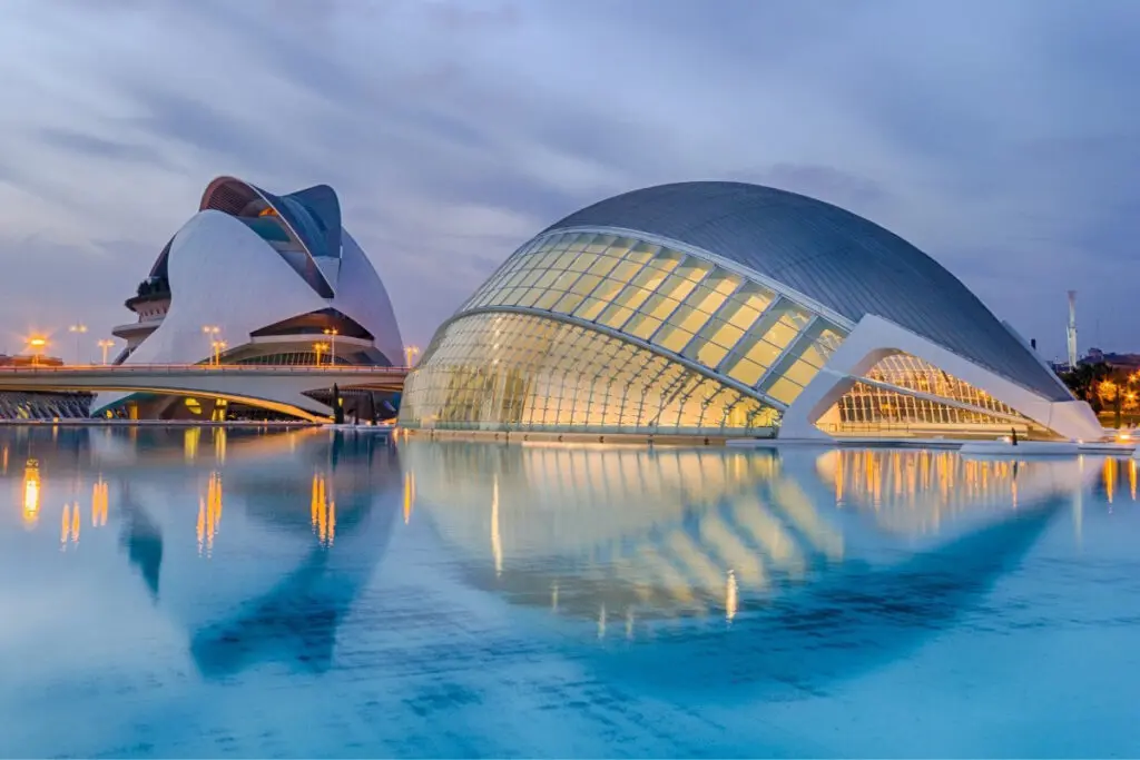 Edificios iluminados junto al agua Edificios modernos iluminados al anochecer se reflejan en una superficie de agua.