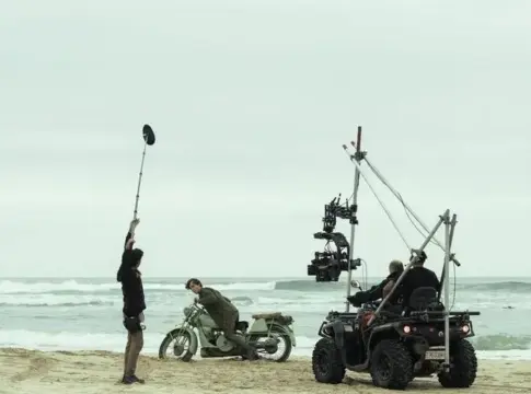 Equipo de rodaje junto al mar Equipo de rodaje con cámara y micrófono junto a una motocicleta en la playa.