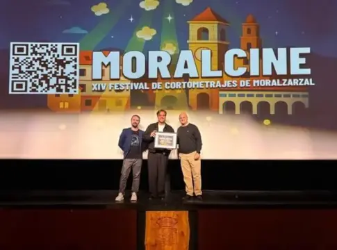 Tres hombres en el escenario de MoralCine Tres hombres posan en un escenario bajo una pantalla del festival MoralCine.