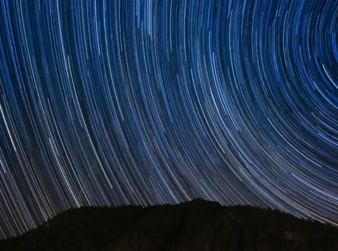 Estelas estelares sobre una montaña oscura primera estrella verde