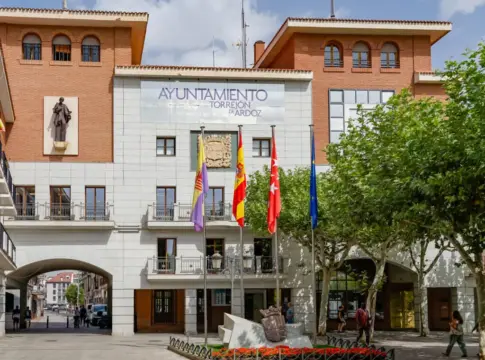Fachada del Ayuntamiento de Torrejón de Ardoz Fachada del Ayuntamiento de Torrejón de Ardoz con banderas y peatones en la plaza