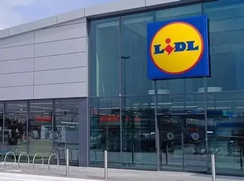 Fachada de una tienda Lidl Fachada acristalada de una tienda Lidl con el logotipo visible sobre la entrada.