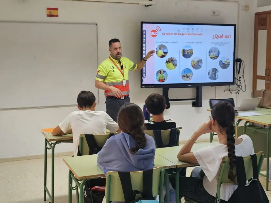 Un formador del Servicio de Urgencias Canario presenta una diapositiva ante estudiantes en un aula.