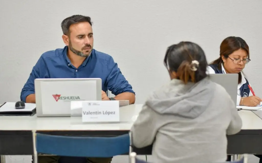 Personas en una selección de Freshuelva Personas sentadas frente a una mesa durante una entrevista, con un portátil de Freshuelva.