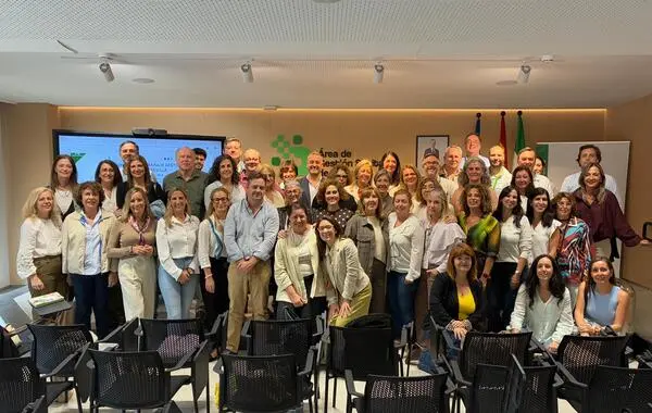 Grupo de asistentes posa en una sala de reuniones con una pantalla al fondo.