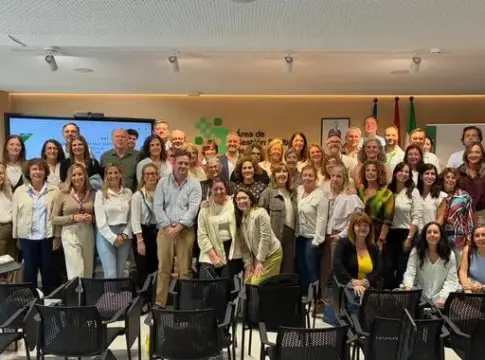 Asistentes en una sala de reuniones Grupo de asistentes posa en una sala de reuniones con una pantalla al fondo.