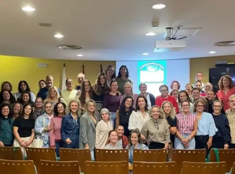 Participantes reunidos en una sala de conferencias Grupo numeroso posa en una sala de reuniones frente a una pantalla de proyección.