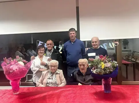 Grupo posa junto a ramos Seis personas posan en un interior detrás de una mesa con dos ramos.