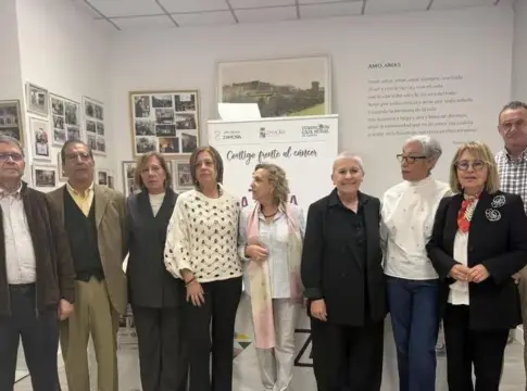 Grupo posando en una sala informativa Nueve personas posan en una sala con paneles informativos y carteles en las paredes