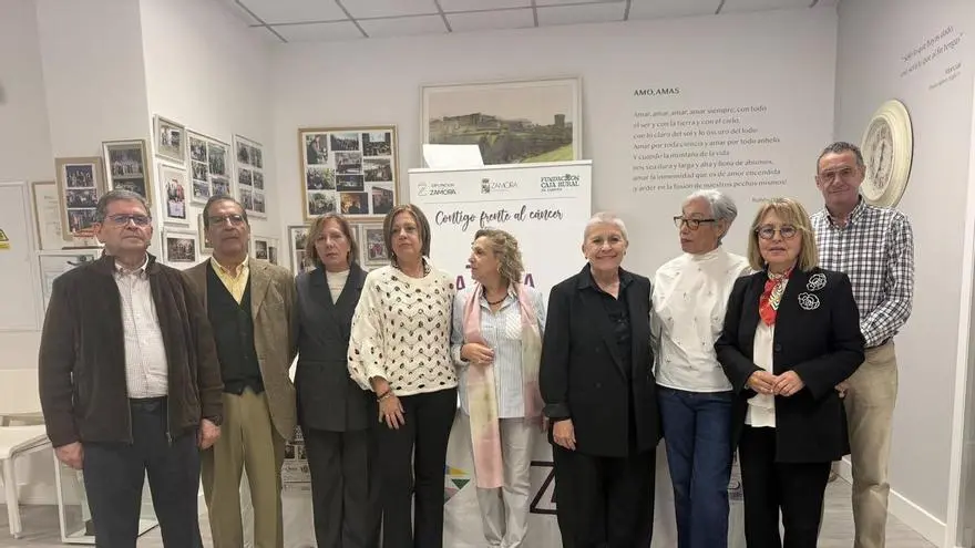 Nueve personas posan en una sala con paneles informativos y carteles en las paredes