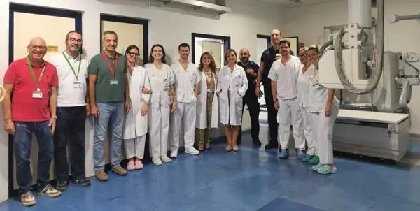 Grupo de personas posa en una sala clínica junto a un equipo de imagen médica.