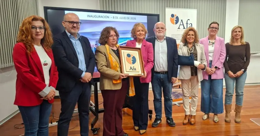 Ocho personas posan en un acto junto a una placa enmarcada con el logotipo de AFA.