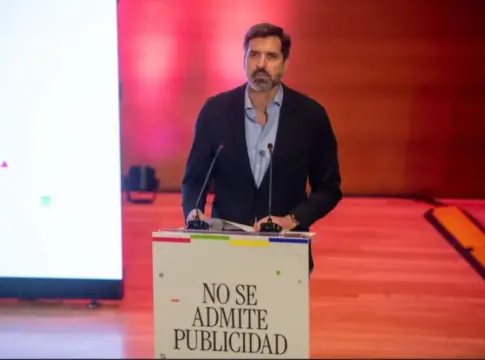 Hombre ante un atril en un escenario Hombre ante un atril con dos micrófonos en un escenario iluminado en rojo