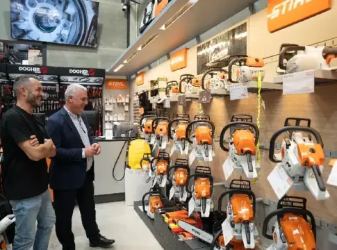 Motosierras expuestas en una tienda Dos hombres observan motosierras expuestas en los estantes de una tienda.