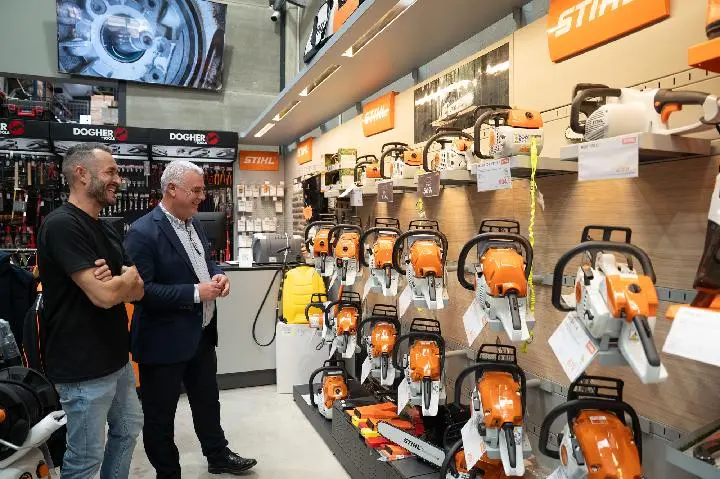 Motosierras expuestas en una tienda Dos hombres observan motosierras expuestas en los estantes de una tienda.