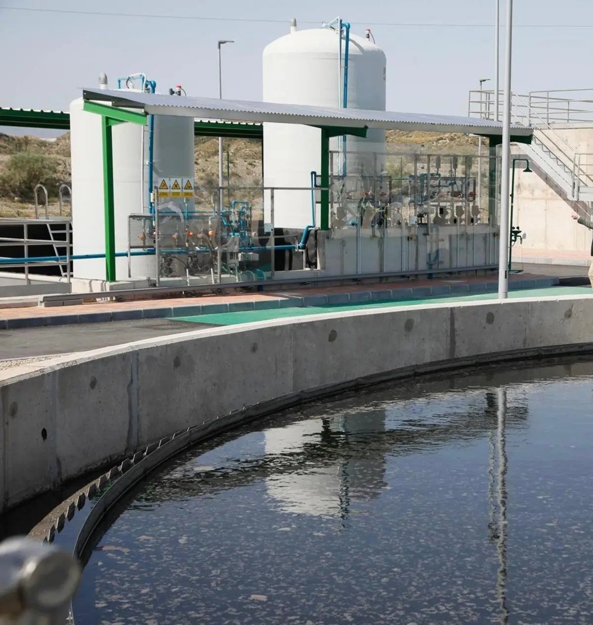 Instalación de tratamiento de agua con depósitos, tuberías y una balsa circular.