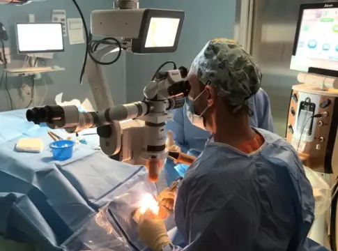 Intervención con microscopio en quirófano Persona con ropa quirúrgica trabaja junto a un microscopio durante una intervención.