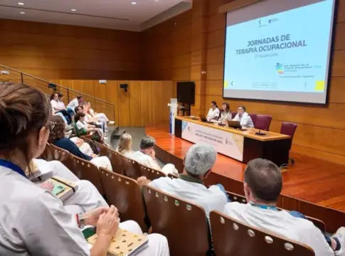 Jornada de terapia ocupacional en auditorio Asistentes escuchan una jornada de terapia ocupacional en un auditorio, con personas sentadas en una mesa.