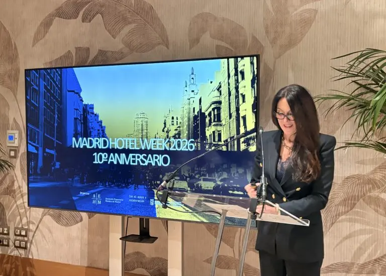 Una mujer junto a un atril, al lado de una pantalla de Madrid Hotel Week.