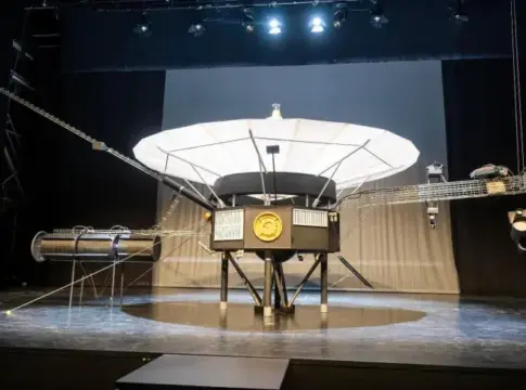 Maqueta de la Voyager 1 en exposición Maqueta de la sonda Voyager 1 expuesta sobre un escenario bajo focos