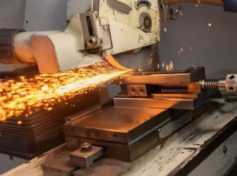Trabajo de una pieza metálica Máquina industrial trabaja una pieza metálica y desprende chispas en un taller