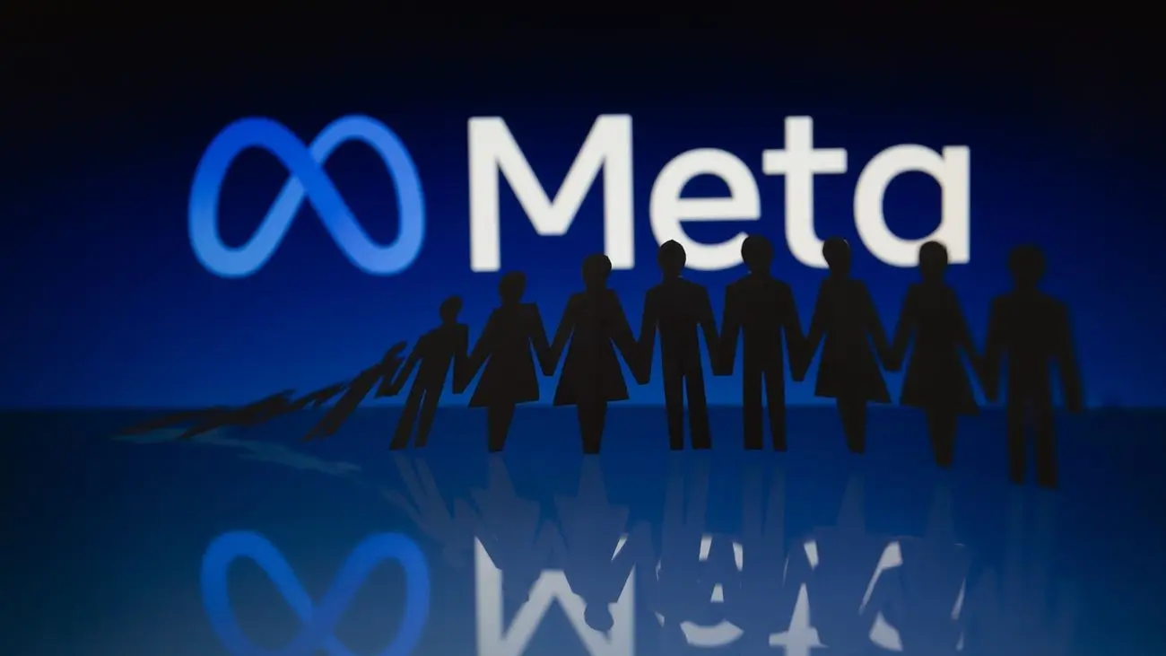 Logotipo de Meta y figuras silueteadas Logotipo de Meta iluminado detrás de siluetas negras de figuras unidas sobre una superficie reflectante.