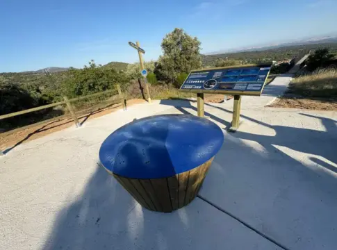 Mesa de observación en un mirador Mirador con mesa circular azul, panel informativo y paisaje de colinas