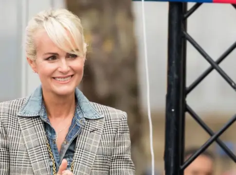 Mujer con blazer de cuadros Mujer sonriente con blazer de cuadros y camisa vaquera junto a una estructura negra