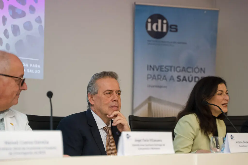 Panel de una jornada de investigación sanitaria Tres personas sentadas en una mesa durante una jornada sobre investigación sanitaria.