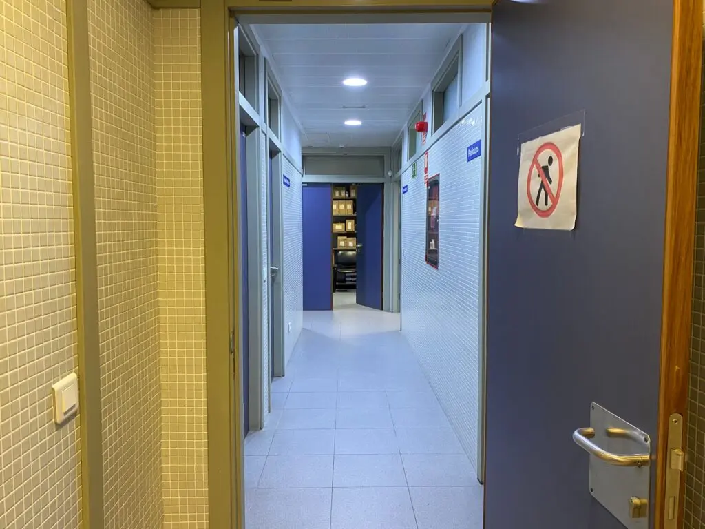 Pasillo interior con puertas abiertas y un cartel de prohibido el paso.