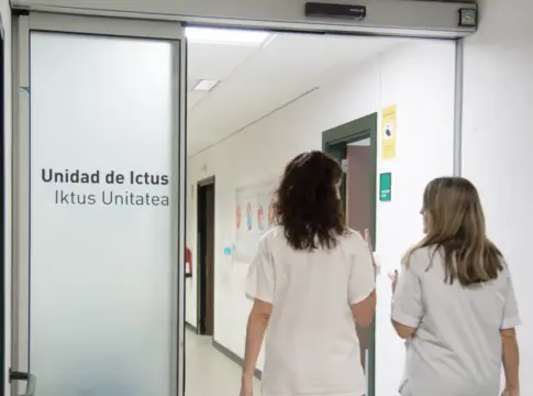 Pasillo de la Unidad de Ictus Dos personas con ropa blanca recorren un pasillo junto al rótulo Unidad de Ictus.
