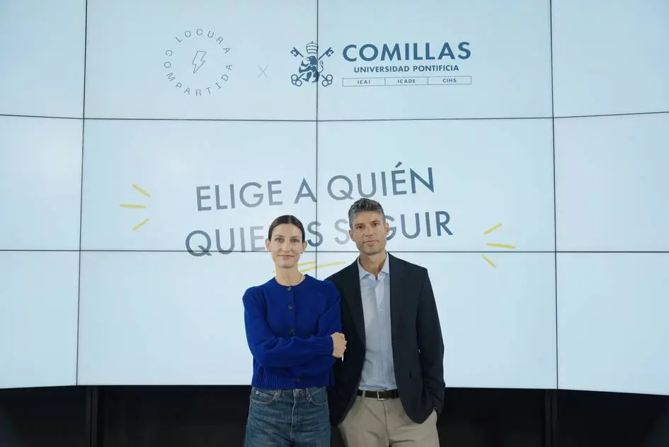 Personas ante los logotipos de Comillas y Locura Compartida Dos personas posan frente a una pantalla con los logotipos de Comillas y Locura Compartida.
