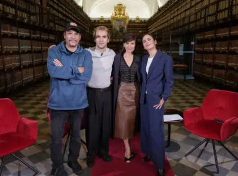 Personas en una biblioteca histórica Cuatro personas posan entre estanterías de libros antiguos y sillones rojos
