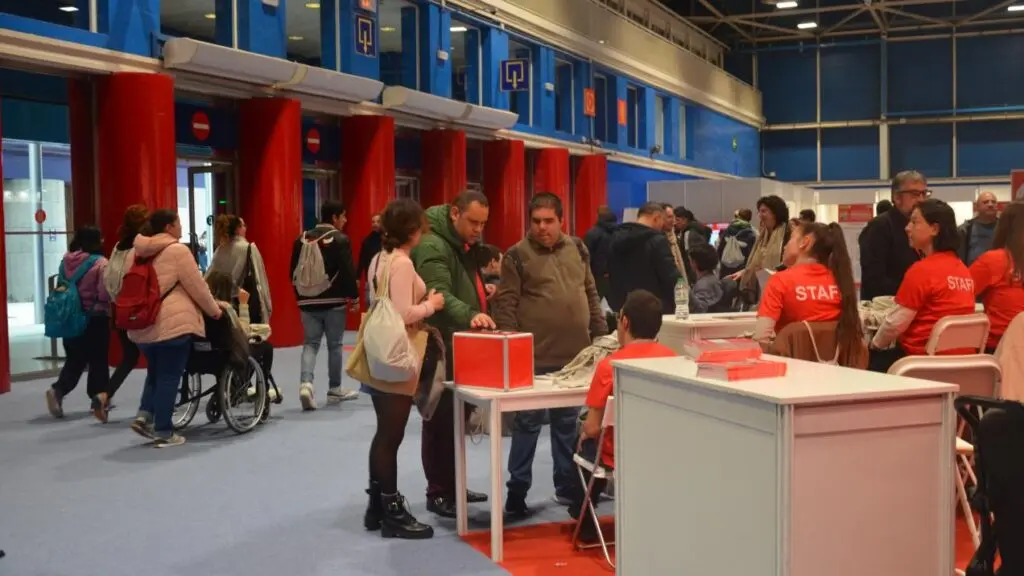Asistentes en una feria de empleo Personas recorren puestos de una feria de empleo, con una persona usuaria de silla de ruedas.