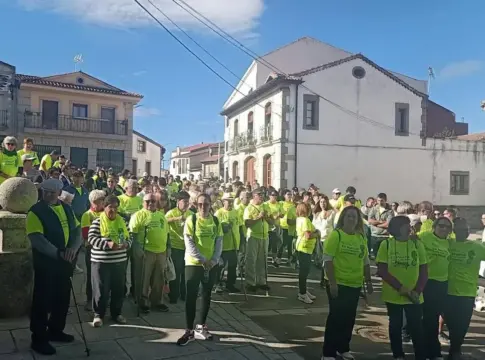 Participantes reunidos para la marcha contra el cáncer Grupo de personas con camisetas verdes reunidas en una calle del pueblo.