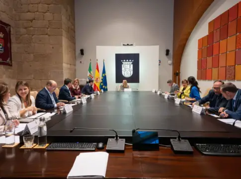 Reunión alrededor de una mesa institucional Personas sentadas alrededor de una larga mesa en una sala de reuniones institucional.